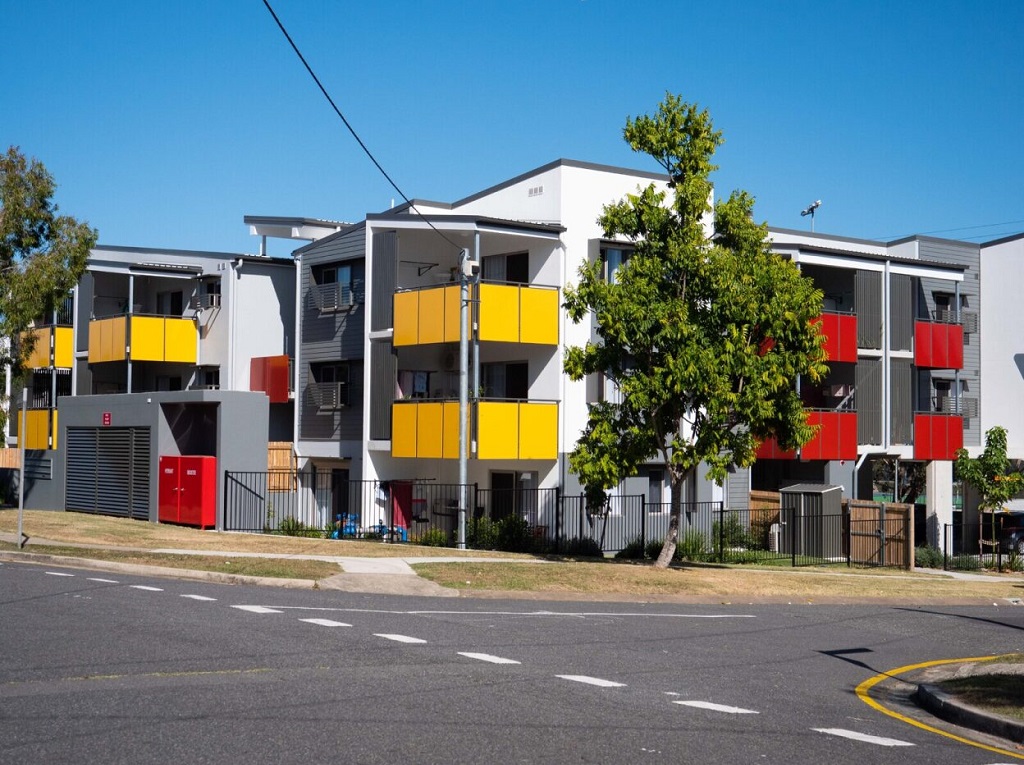 View of the building from the corner, showing bright feature balconies and screening.
