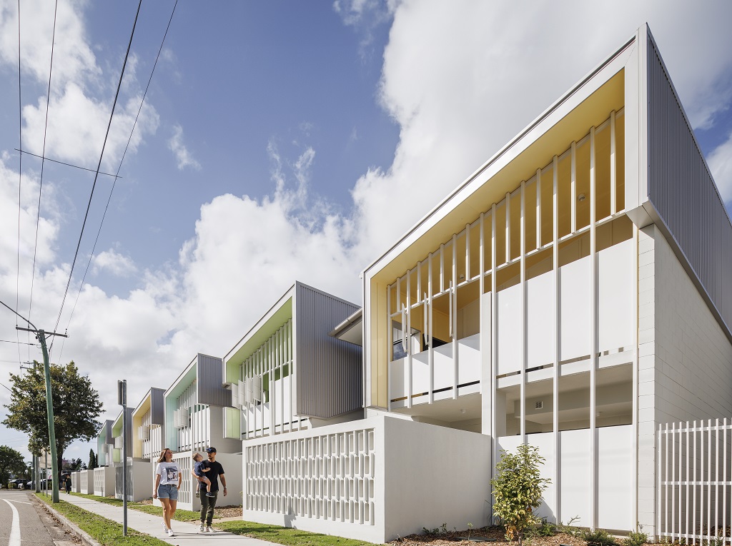 View from the street, showing the townhouse-style apartments with feature colours and breeze blocks. 